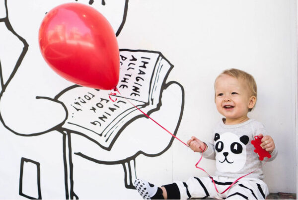 child holding onto red balloon smiling