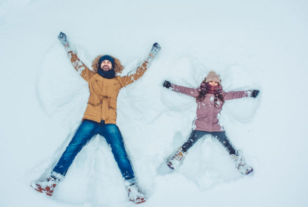 father and child making snow angel