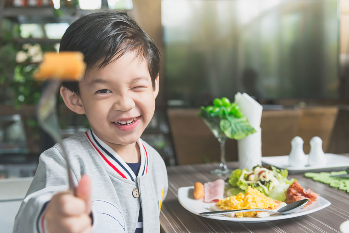 Child eating lunch consisting of cheese, eggs, and healthy greens.